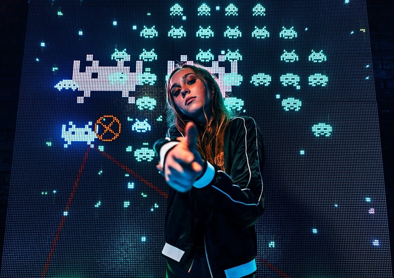 young adult standing in front of arcade game